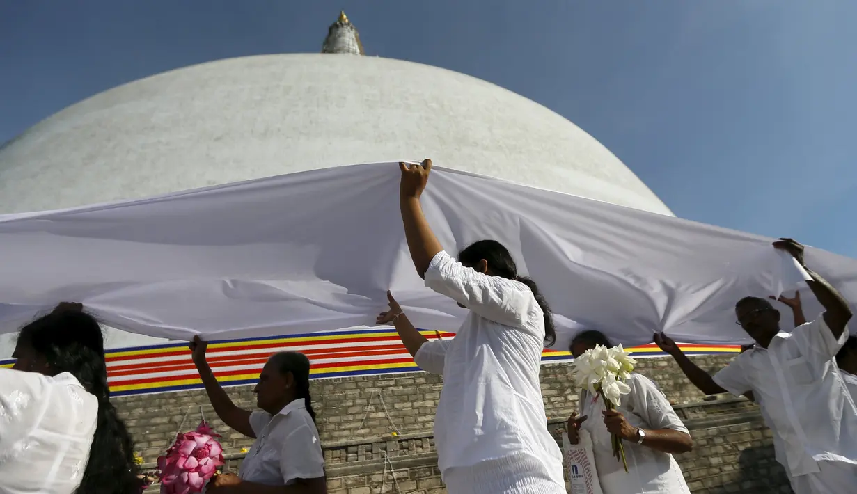 Umat Buddha berdoa di depan Ruwanweli maha Seya pada hari Poya untuk menandai kunjungan kedua Buddha ke Sri Lanka, di Anuradhapura (21/4). Hari Poya dirayakan menyambut bulan purnama. (REUTERS/Dinuka Liyanawatte)