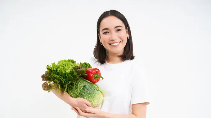 Seorang perempuan memegang sayur-sayuran di tangannya (Foto Dok: Freepik/benzoix)