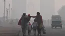 Perempuan India berjalan bersama anak-anak mereka di tengah kabut tebal di dekat Gerbang India di New Delhi  (24/12). (AFP Photo/Prakash Singh)