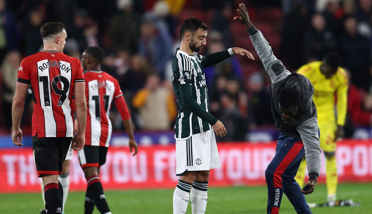 Seorang fans menghampiri gelandang Manchester United, Bruno Fernandes setelah berakhirnya laga pekan ke-9 Liga Inggris 2023/2024 antara Sfheffield United menghadapi Manchester United di Bramall Lane, Sheffield, Minggu (22/10/2023) dini hari WIB. (AFP/Darren Staples)