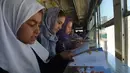 Anak-anak Afghanistan membaca buku dalam bus yang dijadikan perpustakaan keliling di Kabul, 4 April 2018. Perpustakaan keliling itu tidak melintasi jalan-jalan utama yang dilalui dan daerah-daerah menghindari kelompok militan di Kabul. (AFP/Shah MARAI)