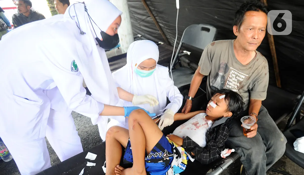 <p>Petugas medis merawat seorang anak korban gempa di RSUD Cimacan, Cianjur, Jawa Barat, Senin (21/11/2022). Hingga berita ini ditulis, Bupati Cianjur Herman Suherman menyebut jumlah korban meninggal akibat gempa magnitudo 5,6 yang mengguncang Cianjur sudah mencapai 56 orang dan 700 lebih lainnya luka-luka. (merdeka.com/Arie Basuki)</p>
