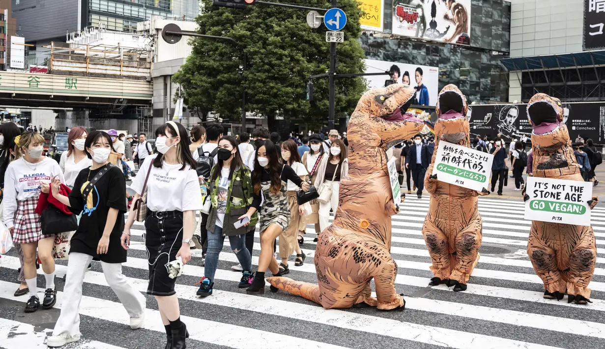 Aktivis kelompok hak hewan PETA mendesak orang untuk menjadi vegan selama protes di Tokyo, Jepang, Rabu (6/10/2021). Dalam aksinya, para aktivis mengenakan kostum dinosaurus. (CHARLY TRIBALLEAU/AFP)
