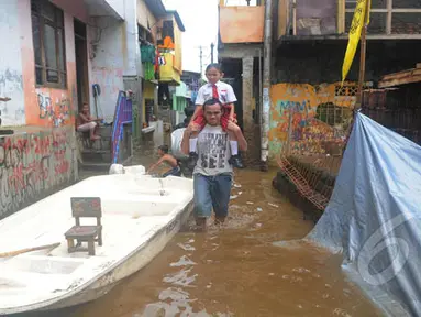 Seorang warga menggendong anaknya melewati banjir di kawasan Kampung Pulo, Jatinegara, Jakarta Timur, Selasa (10/2/2015). Warga tetap beraktivitas meski harus menembus banjir yang melanda pemukiman mereka. (Liputan6.com/Herman Zakharia)