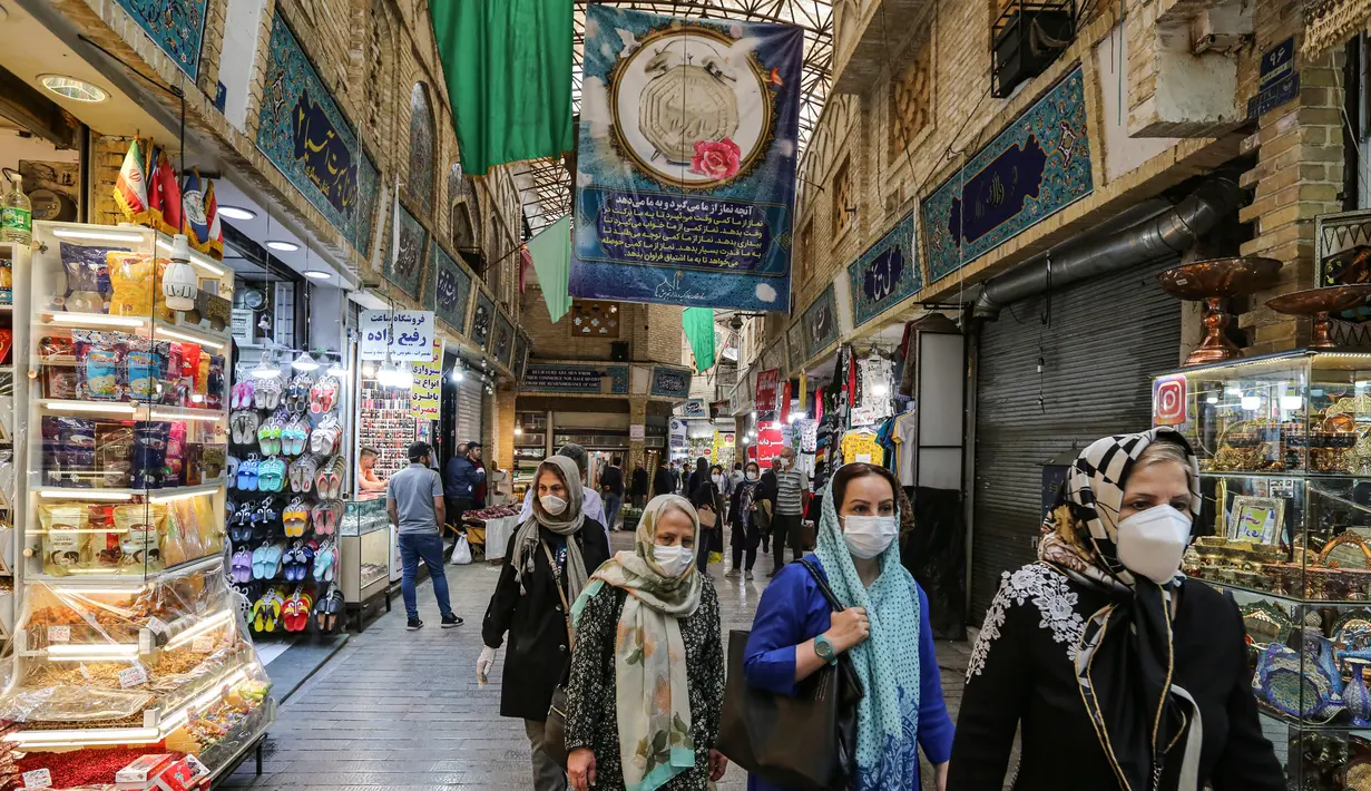Para pembeli mengenakan masker dan sarung tangan lateks, akibat pandemi coronavirus COVID-19, berjalan di pasar Tajrish selama bulan suci Ramadan di Taheran, Iran (25/4/2020). (AFP/Atta Kenare)
