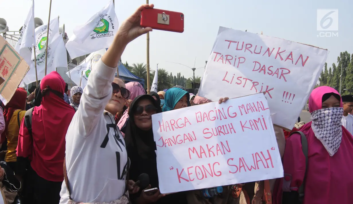 Sejumlah ibu-ibu dari Barisan Emak-Emak Militan Indonesia berswafoto saat menggelar aksi di seberang Istana Merdeka, Jakarta, Rabu (18/7). Massa juga membawa berbagai tulisan berisi tuntutan untuk menurunkan harga bahan pokok. (Liputan6.com/Arya Manggala)