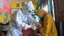 Perawat mengenakan alat pelindung diri saat menyuntikkan vaksin campak kepada seorang anak di Hari Perawat Internasional di Palu, Indonesia, Selasa (12/5/2020). Hari Perawat Internasional diperingati setiap tanggal 12 Mei yang bertepatan dengan kelahiran Florence Nightingale. (MUHAMMAD RIFKI/AFP)