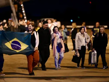 Warga negara Brasil yang melarikan diri dari konflik antara Israel dan Hamas turun dari pesawat militer di Pangkalan Udara Brasilia dalam penerbangan penyelamatan pertama pemerintah Brasil dari Tel Aviv, Rabu (11/10/2023). (EVARISTO SA / AFP)