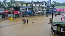 Pihak berwenang setempat telah mengeluarkan peringatan bahaya tanah longsor untuk delapan distrik berisiko tinggi dan mengimbau warga untuk waspada. Tampak dalam foto, warga berjalan di jalan yang terendam banjir setelah hujan deras di Kaduwela, pinggiran Kolombo, pada Jumat 28 November 2025. (Ishara S. KODIKARA/AFP)