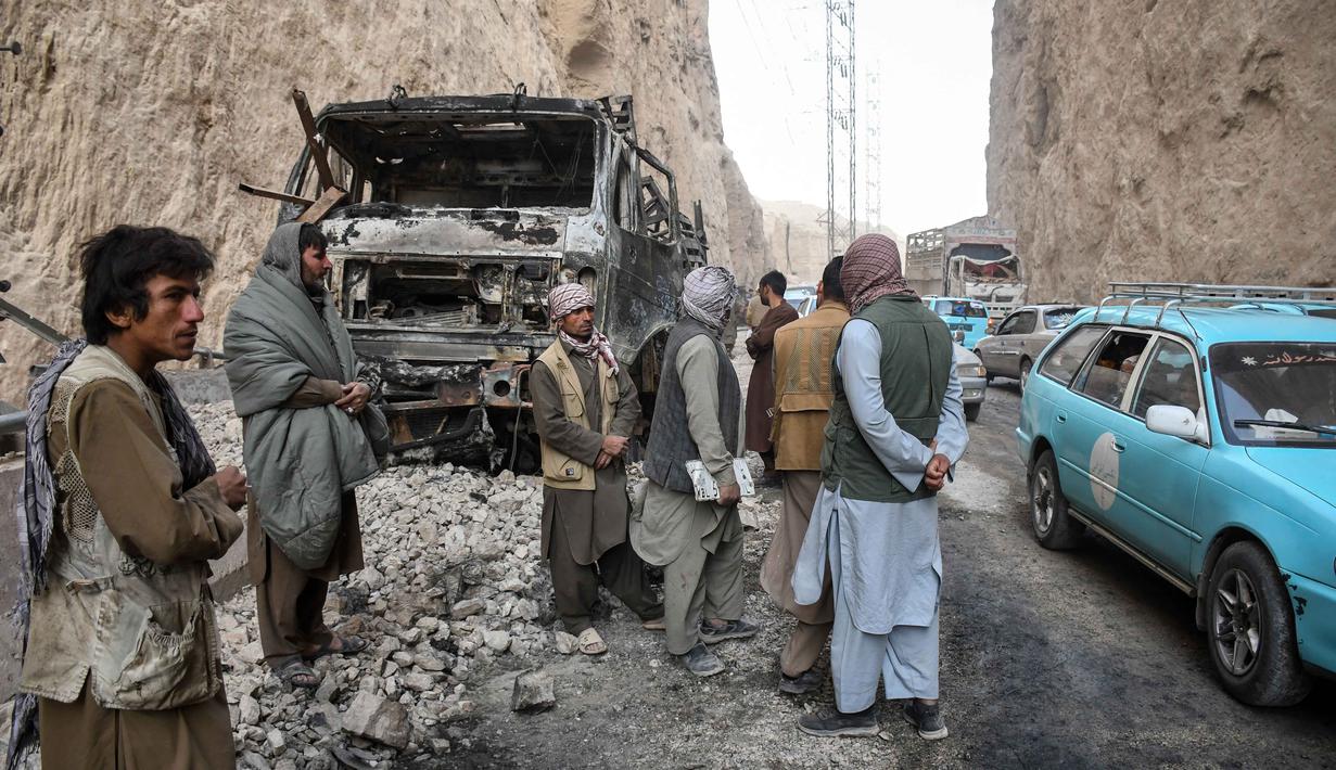 Warga Afghanistan memeriksa sisa-sisa truk yang hangus di sepanjang jalan raya, menyusul gempa bumi di Tang-e Tashkurgan, distrik Khulm, provinsi Samangan, pada Senin 3 November 2025. Gempa ini dikategorikan pada tingkat peringatan oranye, yang menandakan kemungkinan besar terjadinya korban jiwa dalam jumlah signifikan. (Atif Aryan/AFP)