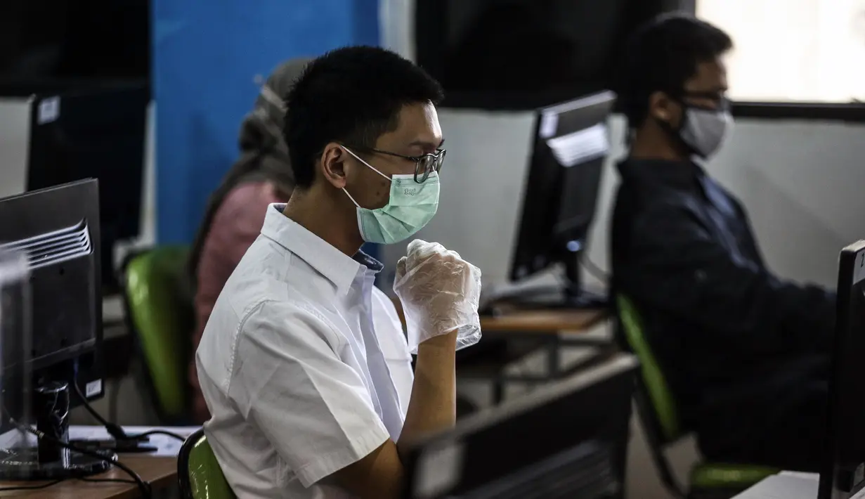 Peserta mengenakan masker dan sarung tangan saat mengikuti Seleksi Bersama Masuk Perguruan Tinggi Negeri (SBMPTN) di Universitan Negeri Jakarta, Minggu (5/7/2020). Sebanyak 42.463 peserta mengikuti SBMPTN dengan prosedur protokol kesehatan. (Liputan6.com/Faizal Fanani)