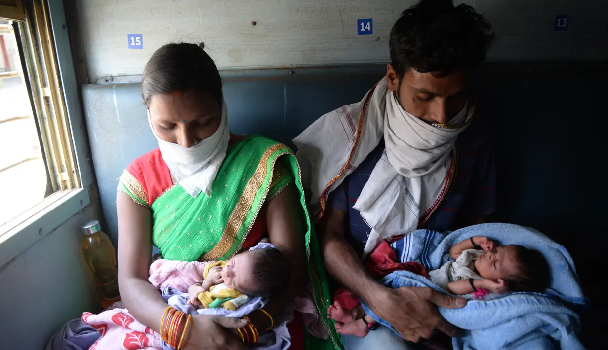 Pasangan buruh migran menggendong bayi ketika menaiki kereta khusus menuju rumah mereka saat masa karantina wilayah (lockdown) nasional diterapkan demi mencegah penyebaran COVID-19 di Jalandhar, Negara Bagian Punjab, India utara, (5//5/2020). (Xinhua/Stringer)