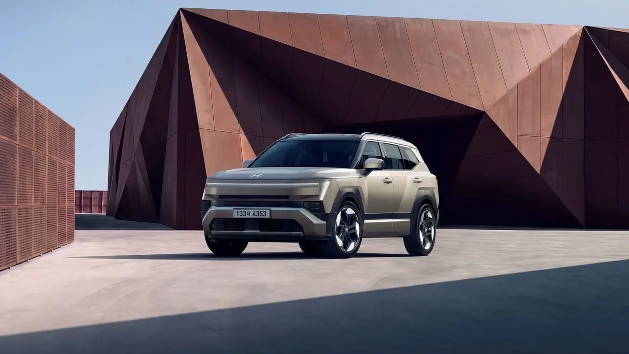 Hyundai Tucson Standar warna Krem-Emas di depan latar arsitektur modern