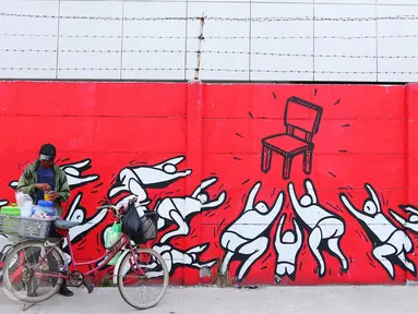 Warga berjualan di depan mural bernuansa politik di Penjaringan, Jakarta, Minggu (7/8). Jelang Pilkada 2017, sejumlah lokasi di Jakarta dihiasi mural politik. (Liputan6.com/Angga Yuniar)
