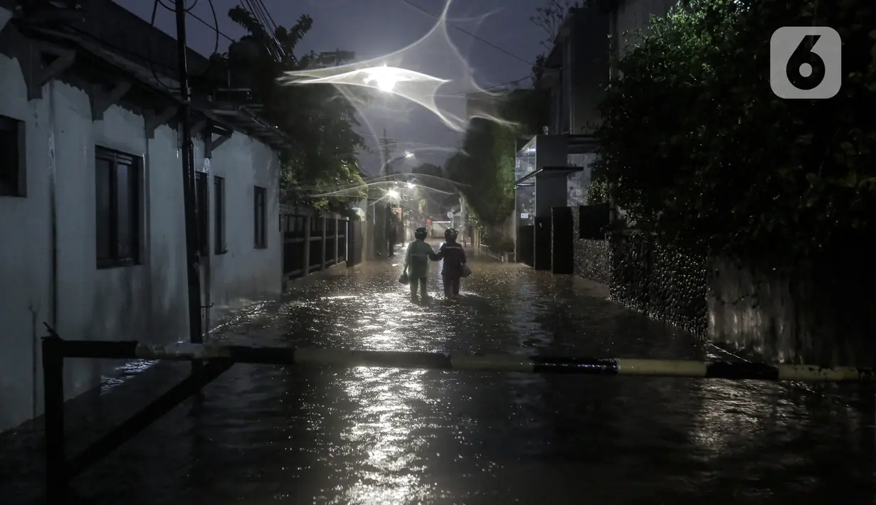 Warga melewati rumah yang tergenang banjir di jalan Bank, Jakarta Selatan, Selasa (4/10/2022). Hujan yang mengguyur wilayah Ibu Kota Jakarta mengakibatkan banjir menggenangi kawasan Kemang, Jakarta. (Liputan6.com/Johan Tallo)