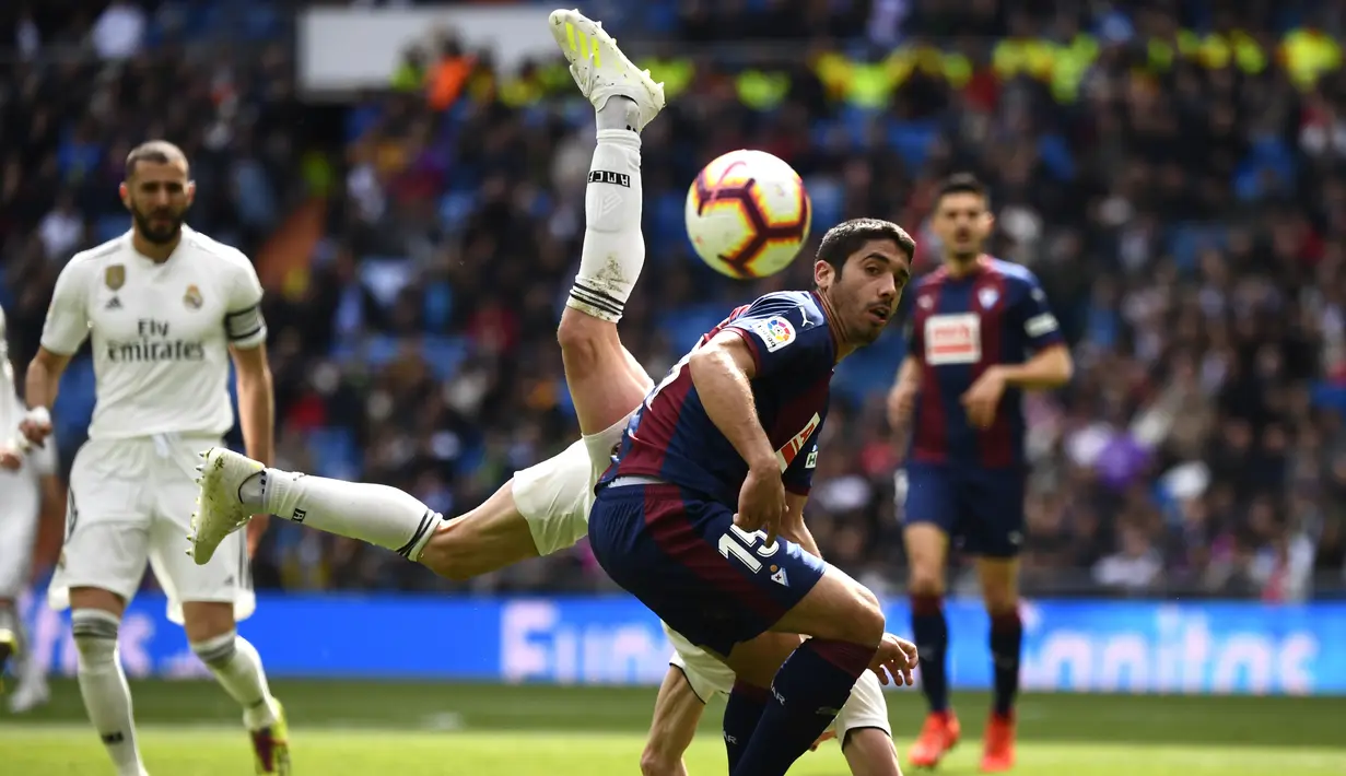 Striker Real Madrid, Gareth Bale, berebut bola dengan bek Eibar, Jose Angel, pada laga La Liga di Stadion Santiago Bernabeu, Sabtu (6/4). Real Madrid menang 2-1 atas Eibar. (AFP/Gabriel Bouys)