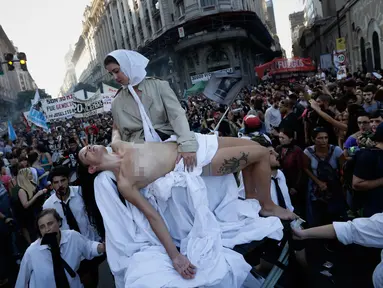 Seorang wanita bertelanjang dada saat menggelar aksi teatrikal yang melambangkan ibu Plaza de Mayo saat pawai parade peringatan 41 tahun kudeta militer di Buenos Aires, Argentina (24/3). (AP Photo/Victor R. Caivano)