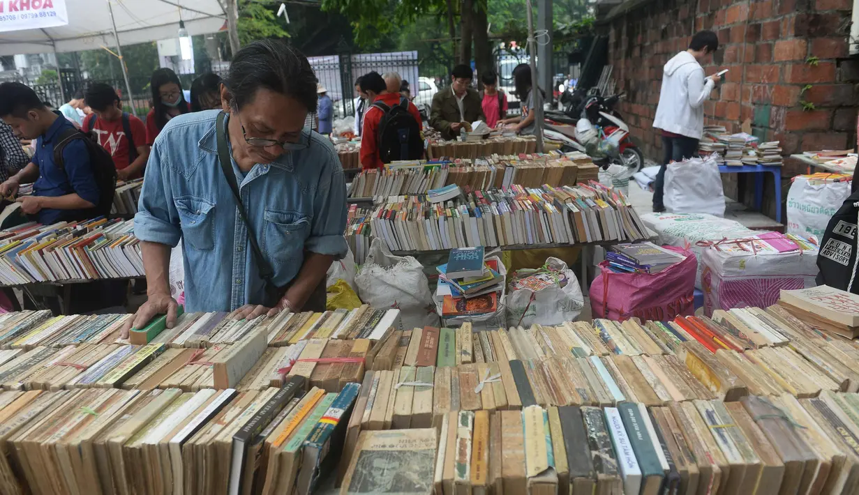 Seorang pria mencari buku selama pameran buku bekas di Hanoi, Vietnam  (26/10).( AFP Photo/Hoang Dinh Nam)