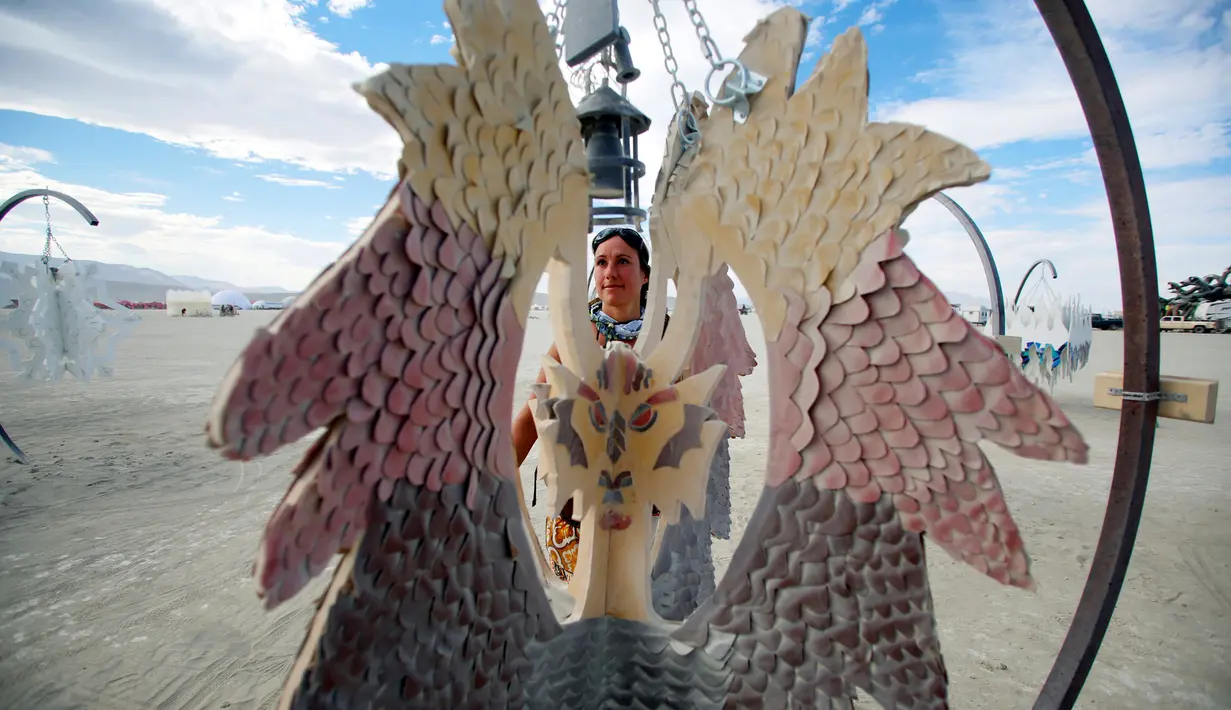 Sandra Mallet melihat karya seni instalasi menyerupai sayap burung di Festival Burning Man, di padang pasir Black Rock, Nevada, Amerika Serikat. (29/08). Karena bersifat eksperimental, festival ini menetapkan sejumlah aturan. (REUTERS/Jim Urquhart)