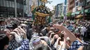 Para peserta membawa kuil portabel atau "Mikoshi" pada Festival Sanja Matsuri di luar kuil Sensoji, Tokyo, Minggu (20/5). Sanja Matsuri adalah festival tahunan di distrik Asakusa yang diadakan pada akhir pekan ketiga pada bulan Mei. (AFP/Behrouz MEHRI)