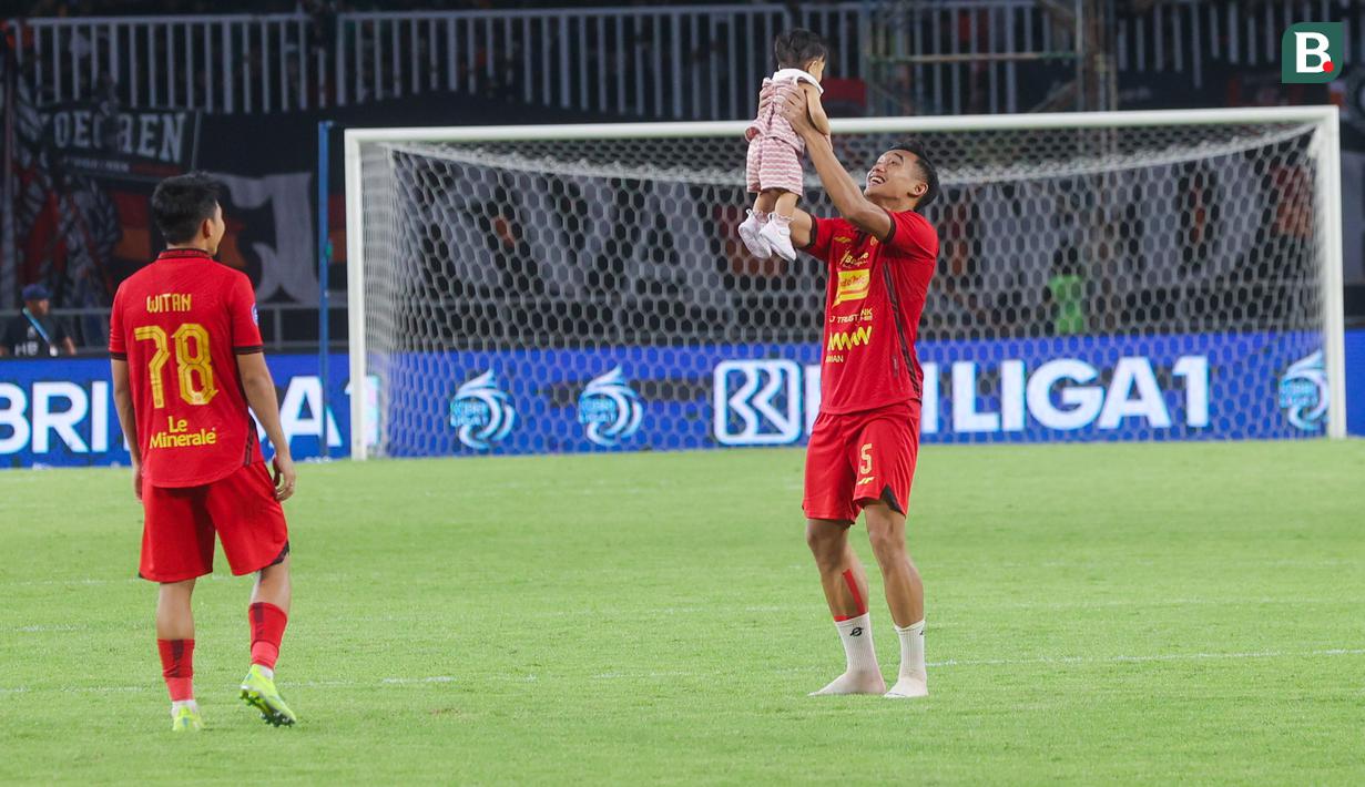 Pemain Macan Kemayoran, Rizky Ridho, menggendong anak rekan setimnya Witan Sulaeman, Hanina Sulaeman setelah pertandingan Persija Jakarta kontra Persik Kediri pada laga BRI Liga 1 di Stadion Pakansari, Jakarta, Minggu (1/12/2024). (Bola.com/M Iqbal Ichsan)