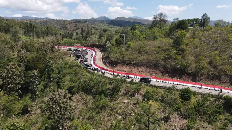 Ratusan warga saat membentangkan bendera raksasa di sepanjang jalan sabuk merah perbatasan RI-Timor Leste (Liputan6.com/Ola Keda)