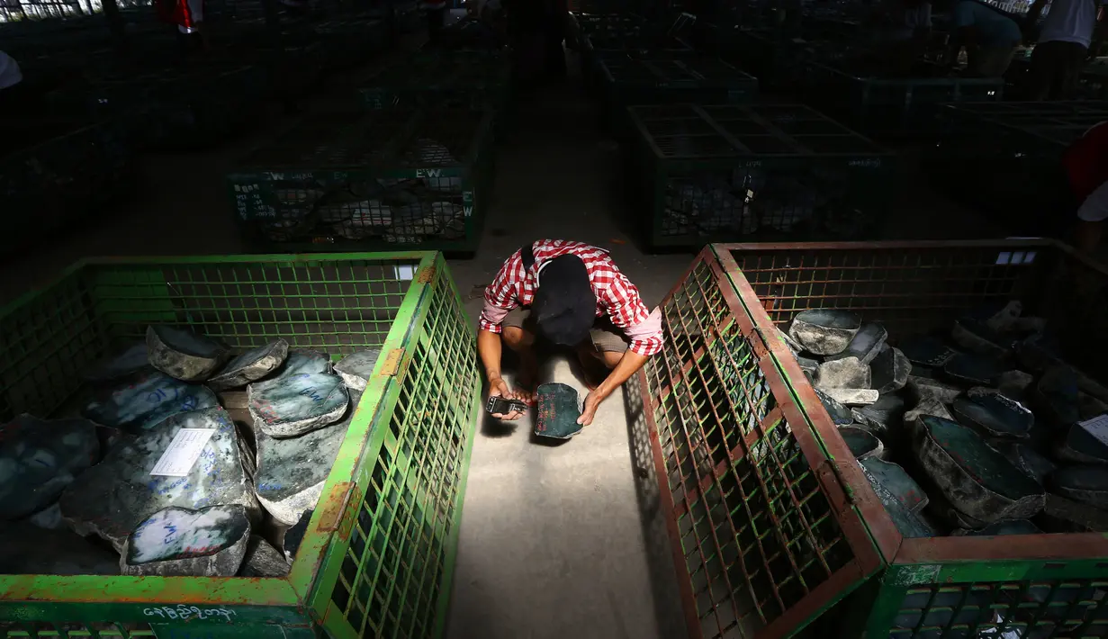 Seorang pedagang memeriksa batu giok dalam bentuk bongkahan yang ditampilkan selama Gems Emporium di Naypyitaw, Myanmar, Selasa (13/11). Acara tahunan tersebut dimulai pada Senin dan akan berlangsung hingga 17 November 2018. (AP/Aung Shine Oo)