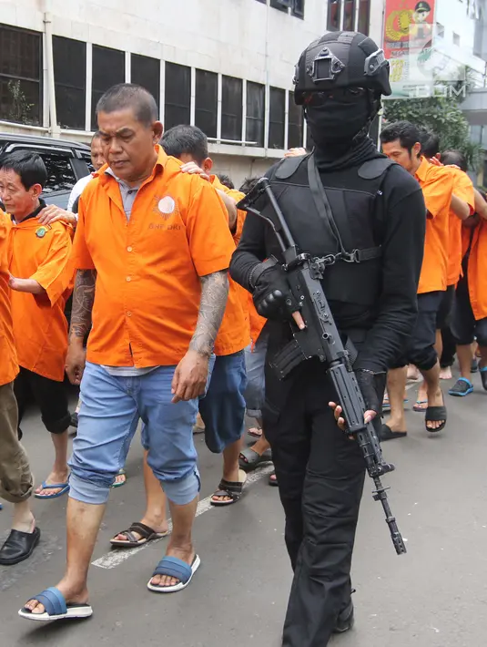 Petugas mengawal pelaku saat rilis perkara tindak pidana perjudian (pai kyu dan koprok) di Polda Metro Jaya, Jakarta, Rabu (14/3). Jatanras Ditreskrimum Polda Metro Jaya berhasil menangkap 85 pelaku tindak pidana perjudian. (Liputan6.com/Arya Manggala)