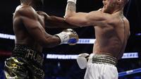 Floyd Mayweather Jr (kiri) melepas pukulan ke Conor McGregor pada pertarungan di T-Mobile Arena in Las Vegas, Nevada, Minggu (27/8/2017). (AP Photo/Isaac Brekken)