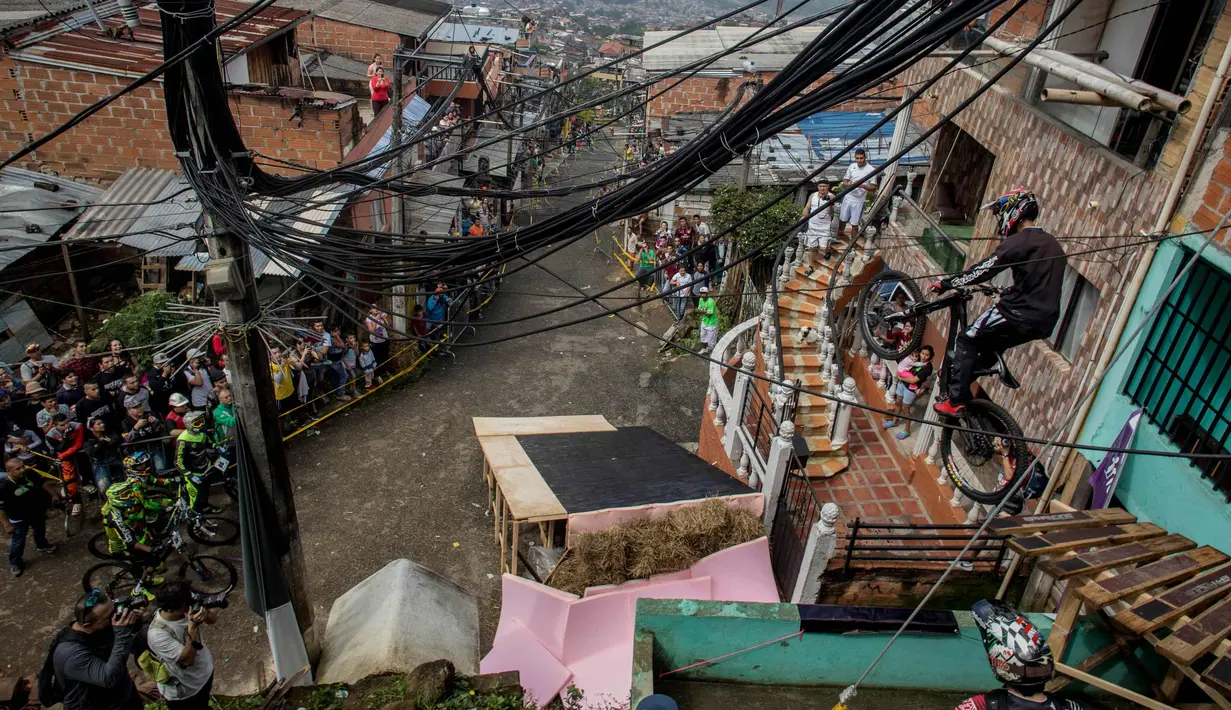 Warga menyaksikan aksi seorang pengendara sepeda saat mengikuti balapan Urban Bike Inder Medellin di gubuk comuna 1 di Medellin, Antioquia department, Kolombia (19/11). (AFP Photo/Joaquin Sarmiento)