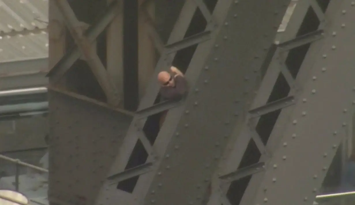 Seorang pria berbaju hitam dan berkaca mata sedang menaiki jembatan Sydney Harbour, Australia, (17/6). Belum diketahui motif apa yang membuat pria tersebut menaiki jembatan yang menjadi landmark Australia tersebut. (SEVEN NETWORK/via REUTERS TV)