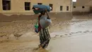 Seorang pria membawa barang miliknya melintasi banjir setelah hujan deras melanda sebuah desa di provinsi Laut Merah Yaman, Houdieda, Jumat,  15 April 2016. (REUTERS/Abdul Jabbar Zeyad)