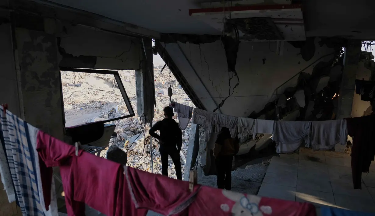 Secara umum, sekitar 80 persen wilayah utara Gaza telah hancur akibat serangan Israel. Tampak dalam foto, anak-anak berdiri di dalam sebuah gedung apartemen yang rusak parah di Jabalia, di bagian utara Jalur Gaza, meskipun kerusakan yang parah, pada Minggu 7 Desember 2025. (AP Photo/Jehad Alshrafi)