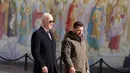 Presiden Ukraina Volodymyr Zelensky (kanan) bersama Presiden AS Joe Biden (tengah) saat setelah tiba di Kyiv, Ukraina pada 20 Februari 2023. Keduanya mengunjungi Wall of Remembrance of the Fallen for Ukraine di Kyiv. Kunjungan Biden dilakukan jelang peringatan satu tahun invasi Rusia. (Dimitar DILKOFF/AFP)