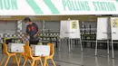 Pemilih memberikan suara dalam pemilu di TPS Sekolah Tinggi Chung Cheng, Singapura, Jumat (10/7/2020). Pemilu di tengah pandemi COVID-19, warga Singapura memberikan suara mereka dengan mengenakan masker dan sarung tangan plastik. (AP Photo)