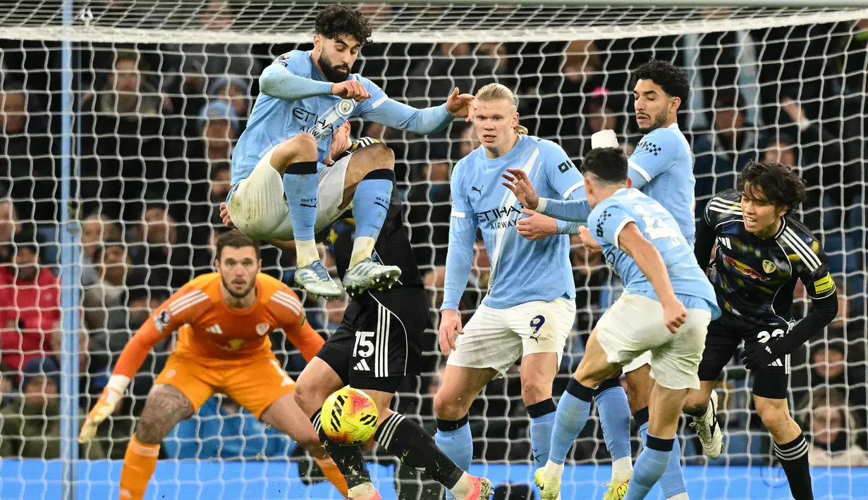 Pemain Manchester City, Josko Gvardiol, melakukan aksi loncat saat Phil Foden melepaskan tendangan ke gawang Leeds United pada pekan ke-13 Premier League 2025/2026 di Etihad Stadium, Sabtu (29/11/2025) malam WIB. (AFP/Oli Scarff)