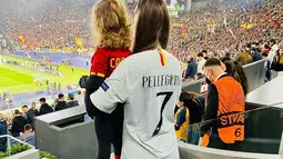 Lorenzo Pellegrini kini menjabat sebagai sebagai kapten AS Roma. Ia identik dengan nomor 7 semenjak didatangkan kembali dari Sassuolo. Jersey Pellegrini pun dipakai oleh Veronica Martinelli saat mendukung sang suami langsung di stadion. Ia tak lupa mengajak buah hatinya dengan Pellegrini. (Liputan6.com/IG/@veromartinel)