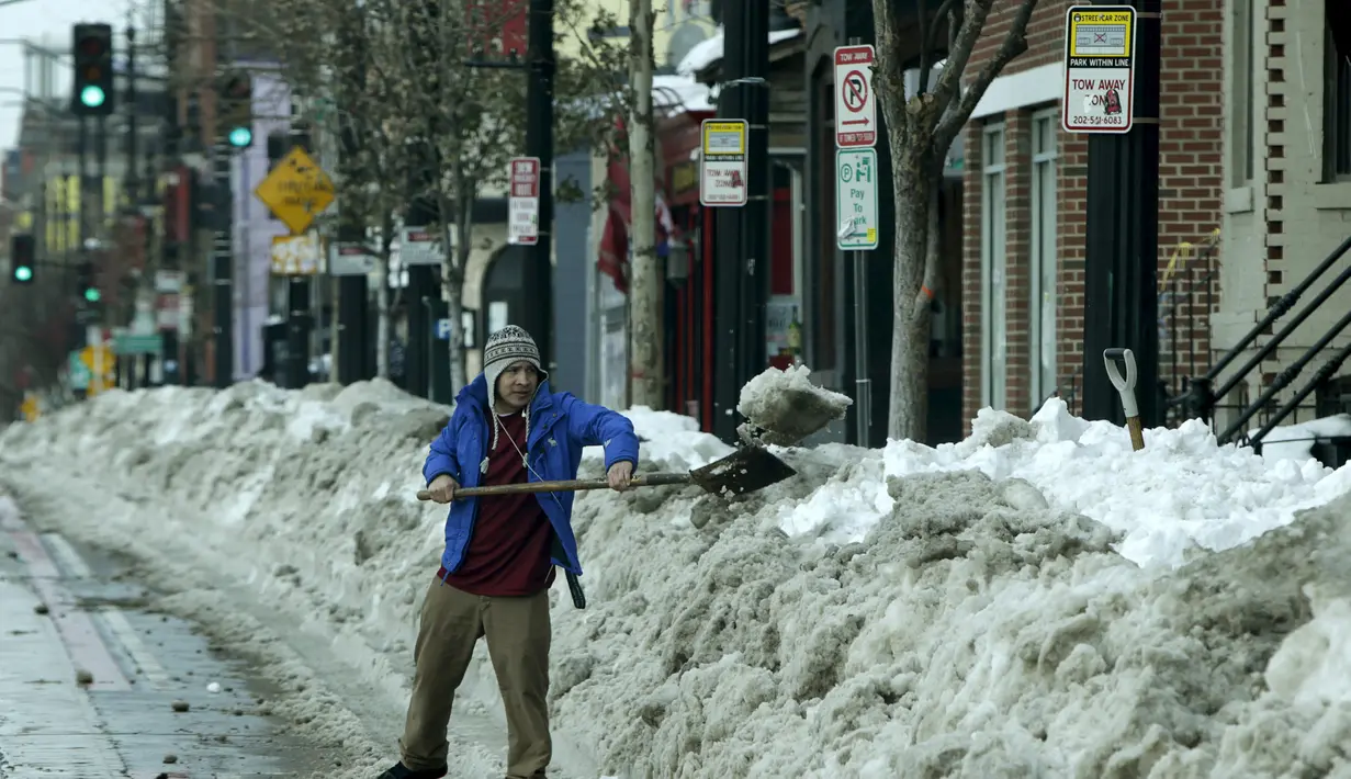 Seseorang sedang membersihkan sisa salju yang menutupi jalan di Washington, Amerika Serikat (26/1/16). Badai ini menyebabkan kerugian miliaran dan menewaskan lebih dari 30 orang. (REUTERS/Gary Cameron)