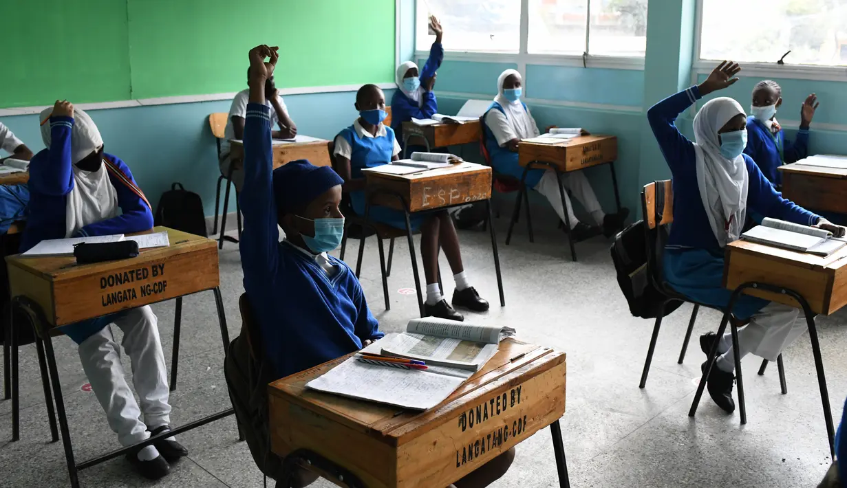 Murid Sekolah Dasar Kongoni mengangkat tangan untuk menjawab pertanyaan saat mereka menghadiri kelas tatap muka di Nairobi, Kenya, Senin (12/10/2020). Kenya membuka kembali sebagian sekolah pada Senin 10 Oktober, setelah ditutup sejak Maret lalu akibat pandemi corona COVID-19. (Simon MAINA/AFP)