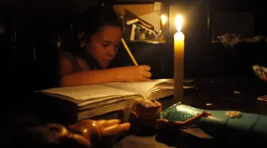 Seorang anak belajar dengan menggunakan lilin akibat pemadaman listrik di San Cristobal, Venezuela, Senin (25/4). Venezuela menerapkan pemadaman listrik selama empat jam sehari untuk menghadapi krisis energi yang memburuk. (REUTERS/Carlos Eduardo Ramirez)