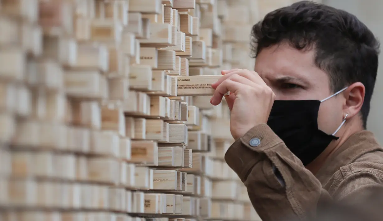 Seorang pria mengambil sebuah balok kayu dari "The Disappearing Wall" di Grand Place, Brussel, Belgia, 3 Oktober 2020. Instalasi seni memperingati 30 tahun reunifikasi Jerman itu terdiri dari 6.000 balok kayu dilengkapi kutipan para seniman dan pemikir dari seluruh dunia. (Xinhua/Zheng Huansong)