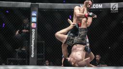 Dua petarung Indonesia Yohan Mulia Legowo (bawah) berusaha melakukan tendangan kepada Victorio Senduk (atas) pada laga One Championship di Jakarta, Sabtu (20/1). Pada laga tersebut Victorio Senduk menang atas Yohan Mulia. (Liputan6.com/Faizal Fanani)