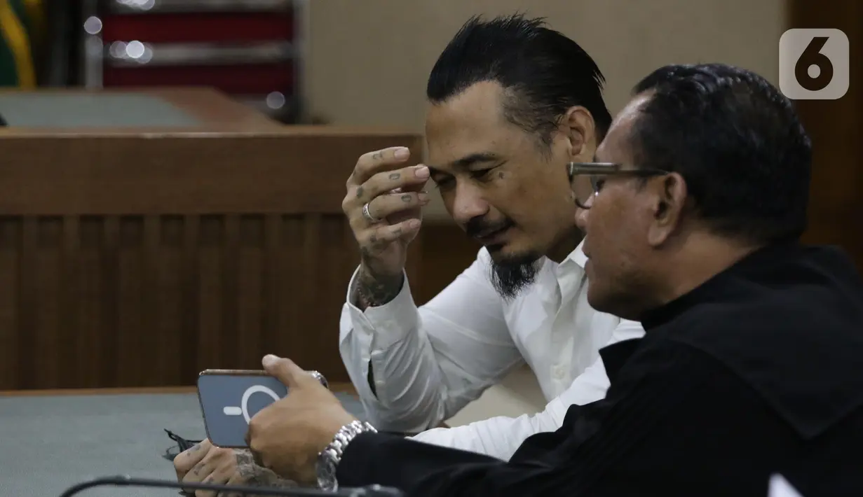Musisi I Gede Ari Astina alias Jerinx SID (kiri) sesaat sebelum sidang pembacaan putusan kasus dugaan pengancaman terhadap Adam Deni di PN Jakarta Pusat, Kamis (24/2/2022). I Gede Ari Astina divonis satu tahun penjara, denda Rp 25 juta subsider satu bulan kurungan. (Liputan6.com/Helmi Fithriansyah)