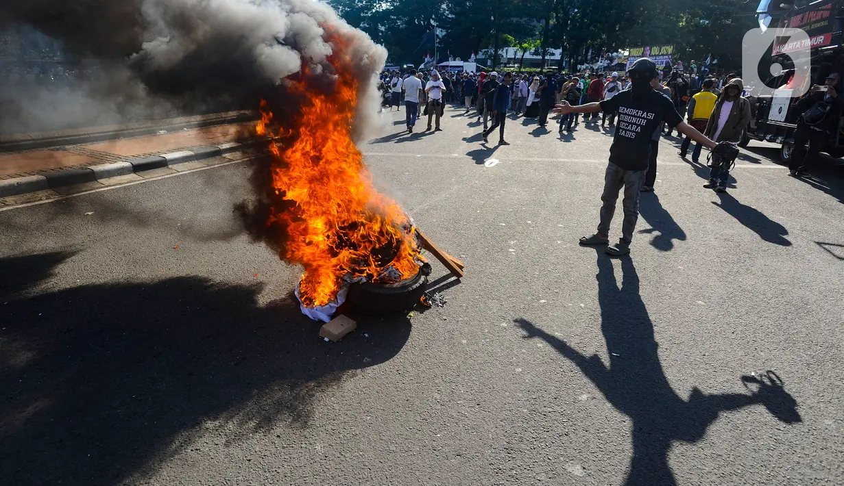 Massa membakar poster dan ban bekas saat aksi terkait putusan sengketa Pilpres di MK, di kawasan bundaran Patung Kuda, Jakarta, Senin (22/4/2024). (merdeka.com/Arie Basuki)