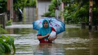 Seorang perempuan melintasi lingkungan yang banjir setelah tiga hari diguyur hujan lebat di Banda Aceh, Aceh, Sabtu (9/5/2020). Banjir akibat intensitas hujan tinggi tersebut mengakibatkan sebagian besar kawasan di ibu kota Provinsi Aceh ini digenangi air. (Photo by CHAIDEER MAHYUDDIN/AFP)