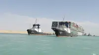 Kapal kargo Ever Given ditemani kapal tunda saat melaju di Terusan Suez, Mesir, Senin (29/3/2021). Pejabat Mesir mengatakan tumpukan kapal yang menunggu untuk transit harus diselesaikan dalam waktu sekitar tiga hari. (Suez Canal Authority via AP)