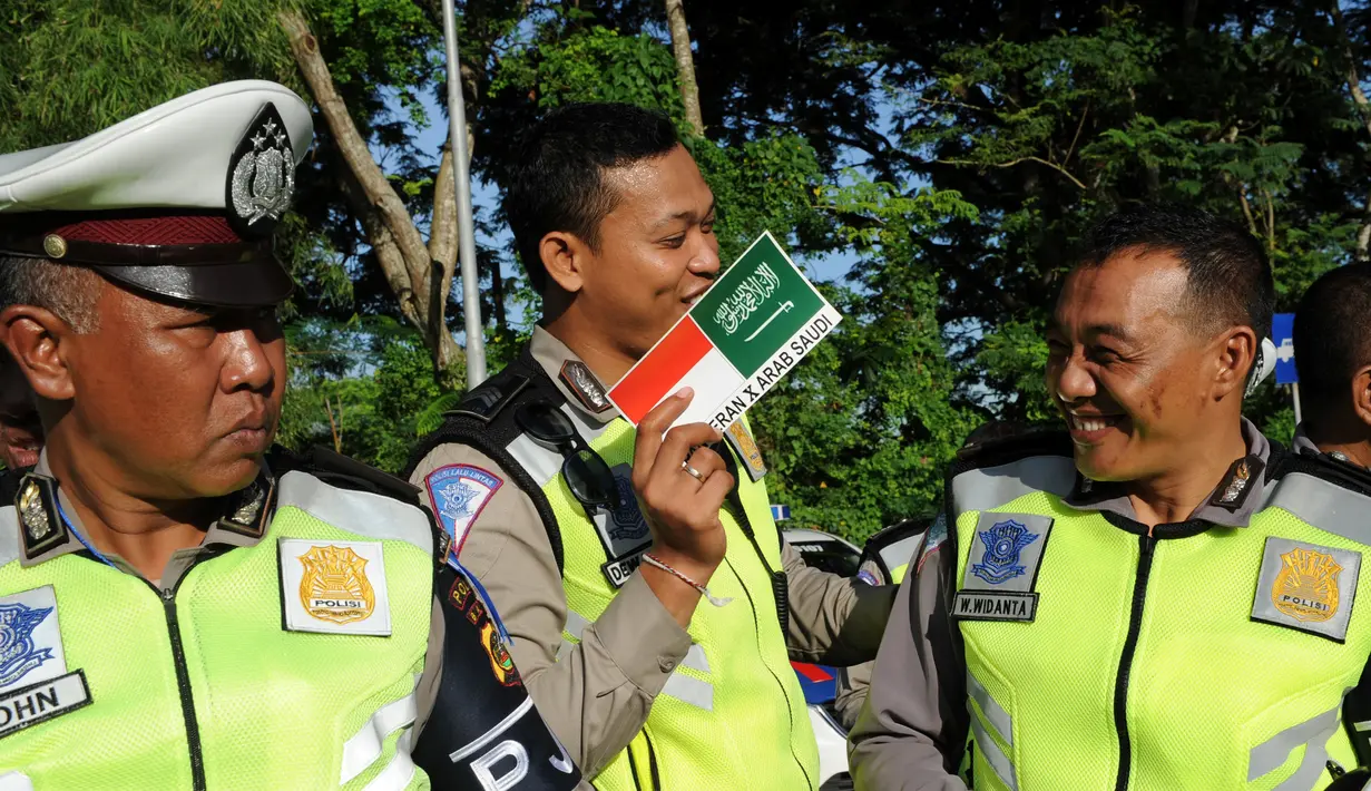 Ekspresi Polisi saat mendapatkan stiker bendera Indonesia dan Arab Saudi selama persiapan menyambut Raja Arab Saudi Salman bin Abdulaziz,Nusa Dua, Bali (2/3). (AFP Photo / Sonny Tumbelaka)
