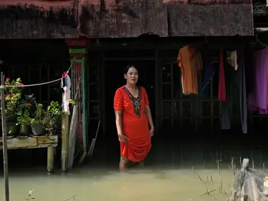 Zuriah berdiri di luar rumahnya yang terendam banjir di Mondoliko, Jawa Tengah, Indonesia, 1 Agustus 2022. Karena tidak mampu untuk pindah ke rumah baru, Zuriah tetap tinggal di rumah itu meski hampir semua tetangganya pindah. (AP Photo/Dita Alangkara)