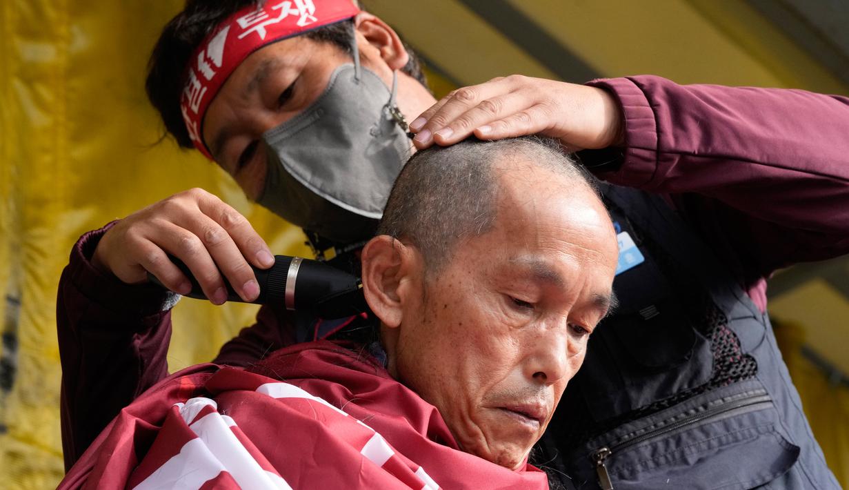 Seorang anggota serikat Solidaritas Pengemudi Truk Kargo mencukur kepalanya saat unjuk rasa menentang perintah pemerintah untuk kembali bekerja pada pengemudi truk semen di Uiwang, Korea Selatan, Selasa (29/11/2022). Pemerintah memperkirakan kerugian harian sekitar 300 miliar won ($224 juta) karena pasokan semen dan bahan bakar untuk pompa bensin menipis. (AP Photo/Ahn Young-joon)