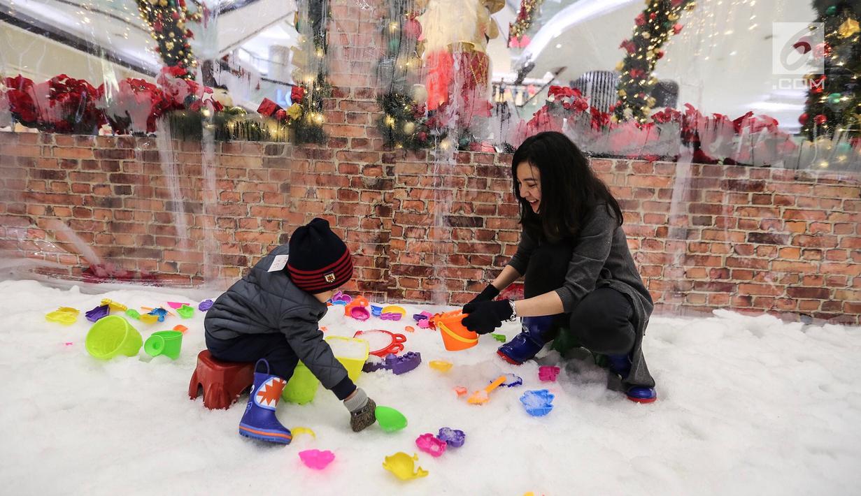 Ibu dan anak bermain salju dari es buatan di Lippo Mall Puri, Jakarta, Kamis (29/11). Wahana bermain Frosty Land di desain dengan suhu di bawah 0 derajat. (Liputan6.com/Fery Pradolo)
